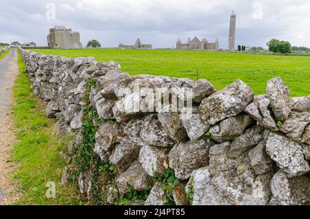 Muro di pietra asciutta che circonda la chiesa di Kilmadough e la torre rotonda. Irlanda Foto Stock