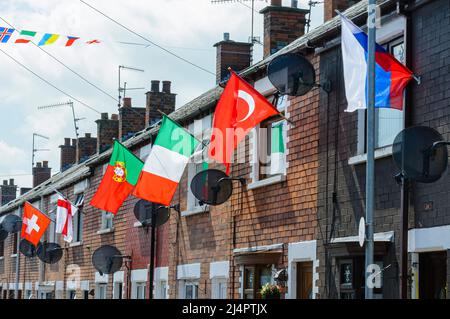 BELFAST, IRLANDA DEL NORD. 04 GIU 2016: Le case di Iris Drive a West Belfast sono decorate con le bandiere di tutti i 24 paesi che si sono qualificati per l'Euro 2016. I residenti hanno organizzato un sweepstake, con ogni casa che deve volare la bandiera del loro paese. Si ritiene che sia la prima volta che le bandiere dell'Inghilterra e dell'Irlanda del Nord sono volutamente volate in questa zona repubblicana di Belfast occidentale. Foto Stock