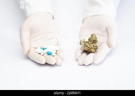 mani di un medico con pillole di industria farmaceutica, e marijuana in boccioli, scelta di medicina naturale, scelta di medicina farmacologica, bac bianco Foto Stock