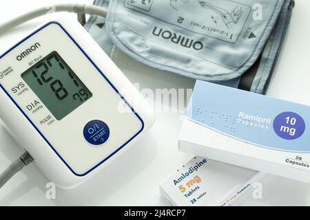 Monitor della pressione sanguigna con bracciale e compresse per la pressione sanguigna alta. Ramipril e Amlodipina compresse per la pressione sanguigna. Sfondo bianco. Foto Stock