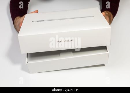 Saratov, Russia - 26 febbraio 2022: Apertura della confezione del nuovo MacBook Air da 13 pollici con processore M1, vista dall'alto unboxing, sfondo bianco Foto Stock