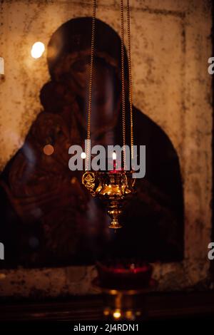 Bell'oro figurò il Pensatore thurible con candela che brucia appeso con catena di fronte alla vecchia icona della Madre Divina. Foto Stock