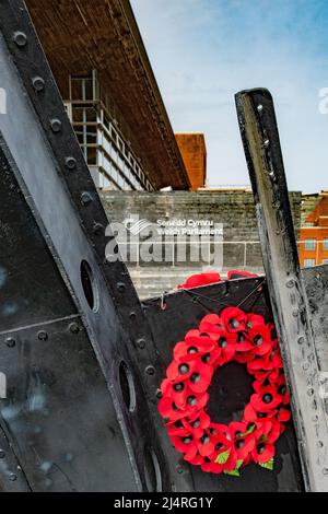 Corona di papavero su un monumento marittimo di fronte al Senedd gallese a Cardiff Bay, Galles, Regno Unito Foto Stock