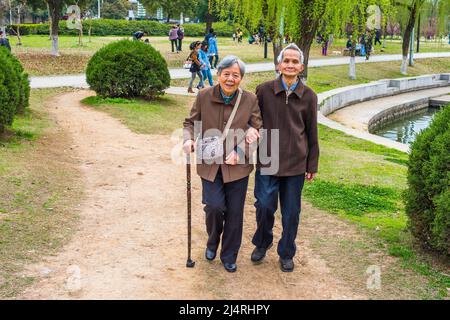 Uomo anziano e Donna che cammina fuori. Una coppia anziana, di 80 anni, che si aiutano a vicenda, braccio in braccio, sta camminando su un parco, una donna che tiene una camminata s Foto Stock