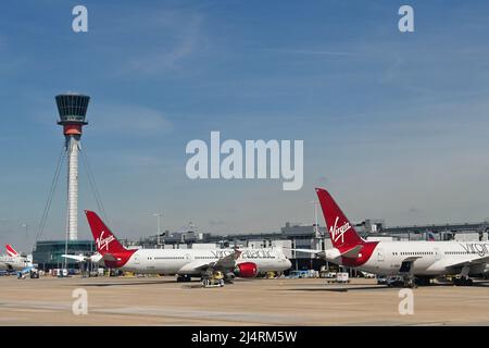 Londra, Inghilterra - Aprile 2022: Virgin Atlantic Airways Boeing Jets presso l'edificio del terminal. A sinistra si trova la torre di controllo del traffico aereo. Foto Stock