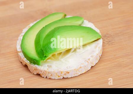 Panino di torta di riso con avocado fresco e formaggio cremoso sul tagliere di bambù. Colazione facile. Dieta alimentare. Panini veloci e sani. Croccante con gustoso ripieno. Snack dietetico sano Foto Stock