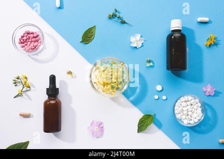 Composizione piatta di varie capsule vitaminiche e integratori dietetici su sfondo blu e bianco. Concetto di complessi vitaminici. Foto Stock