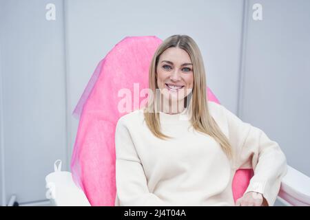 Cliente giovane e allegro che anticipa la procedura cosmetica Foto Stock