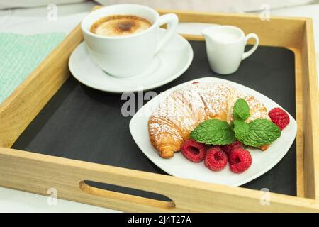 Caffè fresco in tazza bianca, concetto di colazione. Colazione al tavolo con caffè e croissant, luce del mattino dalla finestra. Sfondo con copia s. Foto Stock