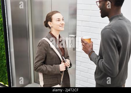 Ritratto di due giovani colleghi che chiacchierano con l'ascensore in un moderno edificio di uffici Foto Stock