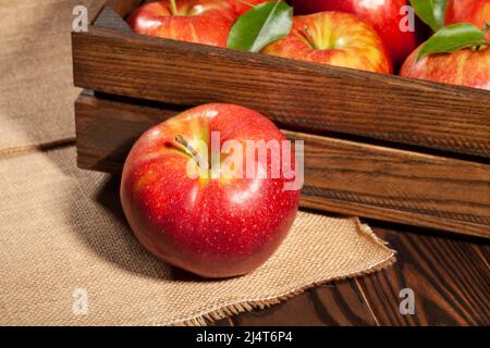 mele rosse in scatola di legno su sfondo di legno marrone Foto Stock