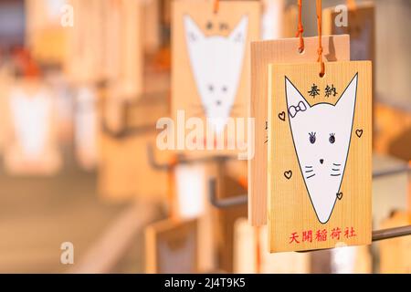 kyushu, giappone - aprile 07 2022: Tavolette votive Ema in legno giapponesi del santuario Tenkai Inari nel tempio di Dazaifu raffigurante una carina silhouette bianca della volpe Foto Stock