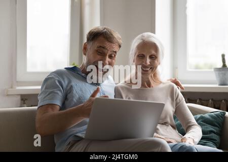 Le coppie anziane leggono le notizie fantastiche si sentono entusiaste fissando il laptop Foto Stock