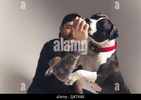Gimme che tratta. Concetto di addestramento del cane. Tatuò il proprietario del cane caucasico e il suo americano Staffordshire Terrier. Foto di alta qualità Foto Stock