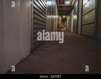Lungo corridoio scuro con porte per lo stoccaggio in un magazzino Foto Stock