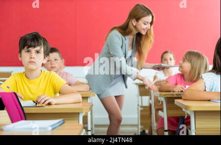 Diligente ragazzo preteen che studia con i compagni di classe a scuola Foto Stock