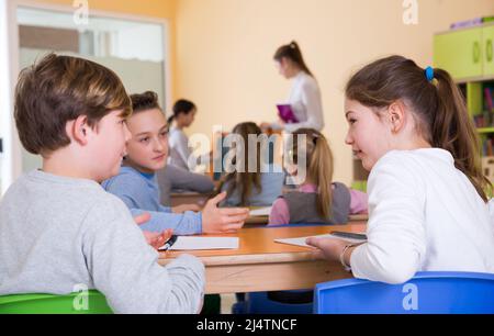 Gli scolari chiacchierano durante la lezione Foto Stock