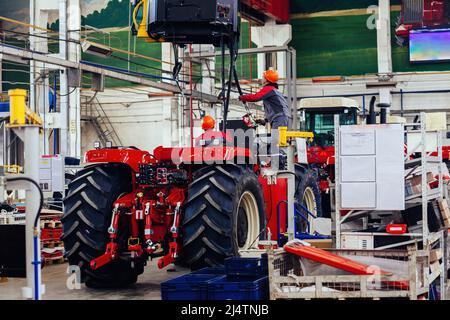 I lavoratori industriali assemblano il trattore agricolo in officina. Foto Stock