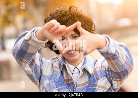 Giovane donna bruna con capelli ricci che fa il segno Framing con le mani Foto Stock