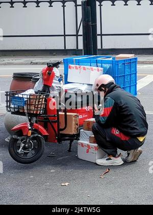 SHANGHAI, CINA - 16 APRILE 2022 - Un corriere di logistica di JD trasporta le merci in linea per i residenti di una Comunità gated nel distretto di Changning, Shanghai, CH Foto Stock