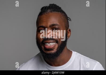 Maschio sorridente che si posa per la fotocamera sullo sfondo grigio Foto Stock