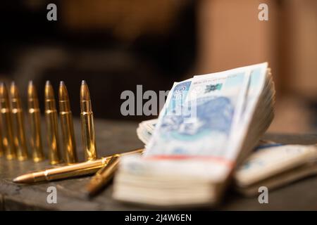 Banconote in carta e cartucce di fucile giacciono su una cassa. Foto Stock