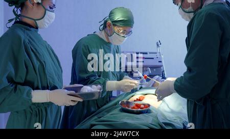 Medico medico chirurgico squadra che esegue la chirurgia paziente, gruppo chirurgo al lavoro in sala operatoria con apparecchiatura di elettrocauterizzazione per l'emero cardiovascolare Foto Stock