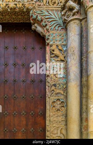 Portale romanico decorato con intagli ornamentali sulla facciata e la porta in legno con ferro da lavoro della chiesa di Santa Maria la Real in Olite, Spagna Foto Stock