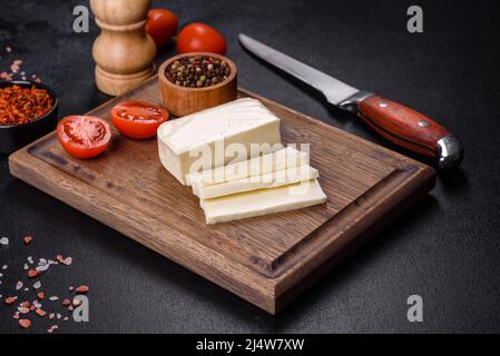 Blocco di mozzarella e pezzi su tagliere di legno Foto Stock