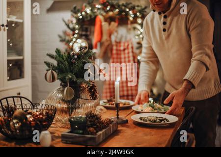 Uomo che prepara cibo delizioso e sano nella cucina di casa per natale. Anatra o oca di Natale e insalate per cena di festa Foto Stock