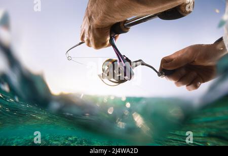 Pesca sfondo sfocato. Pescatore con spinning sul mare. Foto Stock