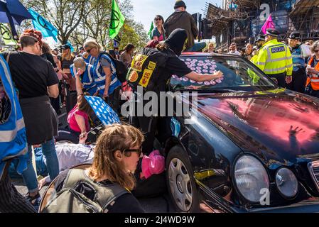 Gli attivisti che fermano un'auto giacendo intorno ad essa e l'uomo che mette adesivi XR sulla macchina, non saremo spettatori, una protesta di estinzione Rebellion che fi Foto Stock