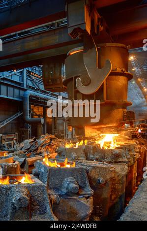 Il metallo liquido viene versato in stampi di acciaio dalla siviera metallurgica. Foto Stock