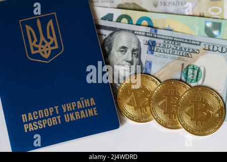 Passaporto urkainiano con monete d'oro bitcoin e banconote diverse. Dollari USA e euro in contanti vicino al passaporto. Valuta Urkaine durante la guerra Foto Stock