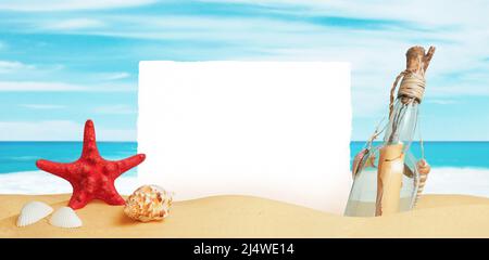 Carta bianca bloccata nella sabbia della spiaggia, circondata da stelle marine, conchiglie e una bottiglia con un messaggio. Pulire la superficie per il testo promozionale Foto Stock