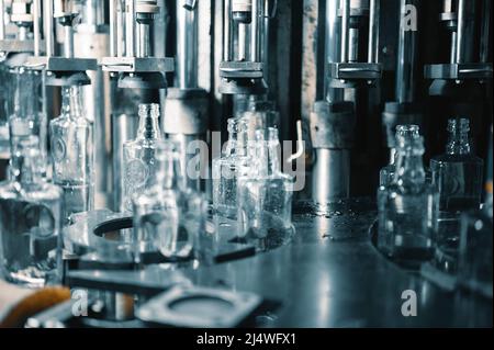 Riempimento di bottiglie di vetro con liquido. Foto Stock