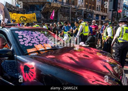 La polizia arriva all'auto bloccata con le impronte di vernice rossa a non saremo spettatori, una protesta della ribellione di estinzione che combatte per la giustizia climatica, Foto Stock