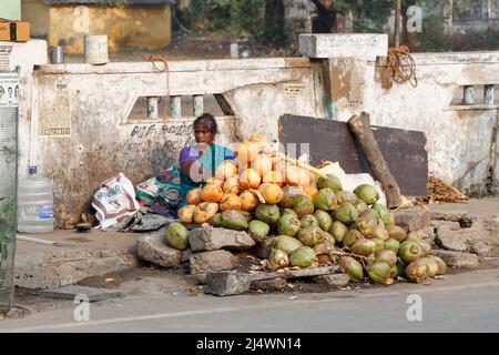 Donna seduta sul marciapiede che vende noci di cocco inTrichy, Tamil Nadu, India Foto Stock