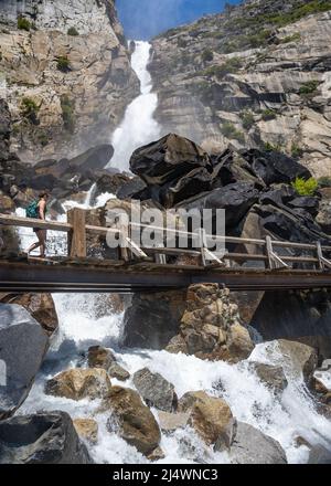 Escursionista che cammina sul ponte delle cascate di Wapama, nel parco nazionale di Yosemite, vicino a Merced, California. Foto Stock