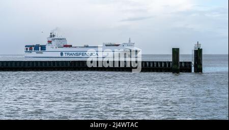 Cuxhaven, Germania - 02.25.2022: Transfennica nave da carico container che naviga in mare dal porto di Cuxhaven in una nuvolosa giornata invernale grigia. Alimentazione c Foto Stock