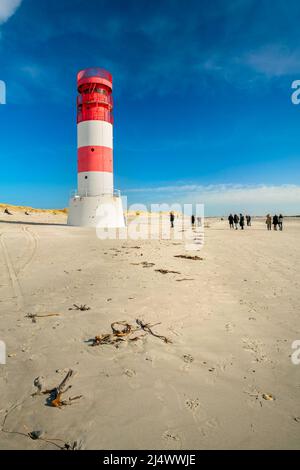 Dune and Heligoland, Germania - 02.27.2022: Colpo verticale di gente che cammina intorno al faro sulla spiaggia dell'isola di Dune, Heligoland, su una bella s Foto Stock