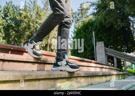 Primo piano gambe camminare giù le scale in un parco della città. Il giovane scende le scale per incontrare i suoi amici. Foto Stock