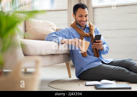 Ritratto di giovane sorridente uomo utilizza lo smartphone a casa Foto Stock