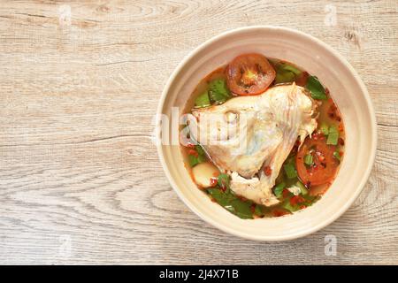 pesce tilapia rosso bollito con pomodoro ed erbe in zuppa di tom yum su ciotola Foto Stock