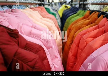 Giacchette colorate in fila su un appendiabiti nel negozio. Nuova collezione di moda primaverile Foto Stock