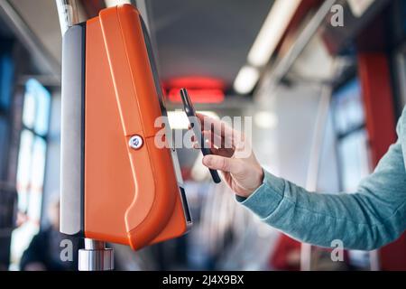 Uomo che acquista il biglietto tramite il portafoglio digitale. Pagamento senza contatto per il trasporto pubblico con telefono cellulare. Foto Stock