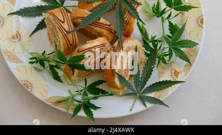 Rotolo dolce con olio di marijuana su piatto bianco. Cucina di cannabis. Disposizione dei deliziosi dessert, vista dall'alto da vicino. Foto Stock