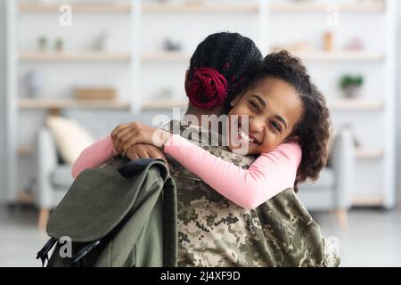 Ritratto di ragazza allegra nera abbracciando la madre e sorridendo Foto Stock