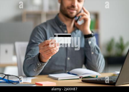 Un uomo d'affari maturo e irriconoscibile che possiede una carta di credito, che ha una conversazione telefonica con un rappresentante del servizio clienti Foto Stock