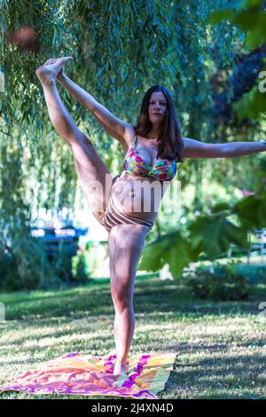 giovane donna incinta che fa yoga all'aperto Foto Stock